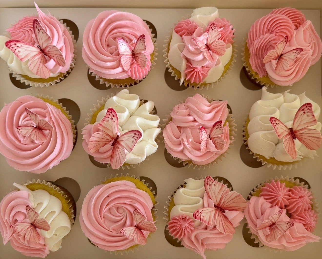 Pink and white cupcakes with buttercream rosettes, flowers and sprinkles