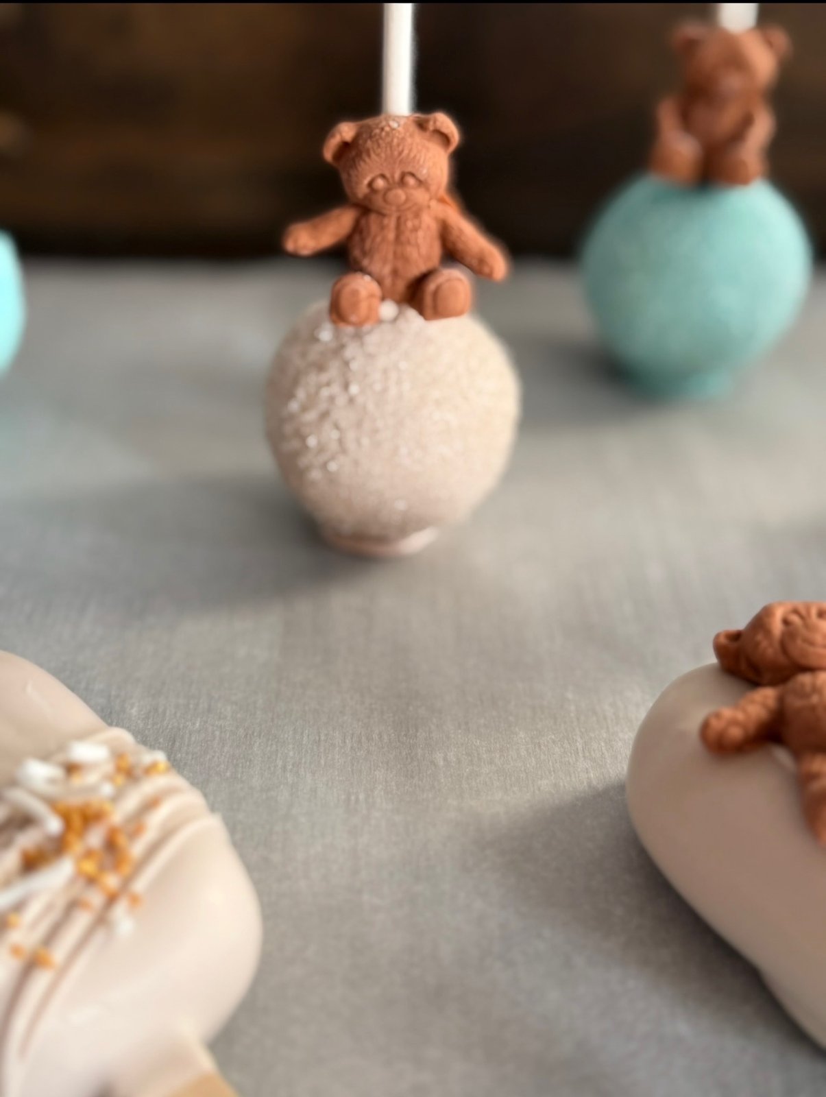 Pastel pink and blue cake pops decorated with small brown teddy bears