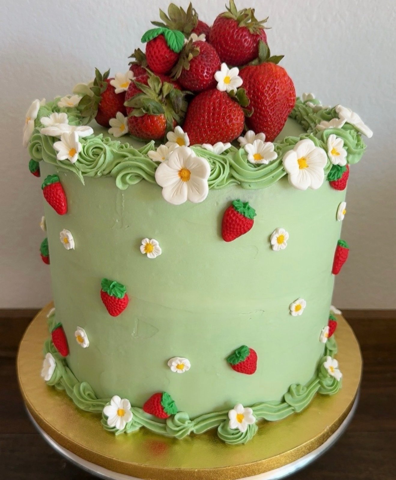 Pale green cake decorated with strawberries and small white daisies